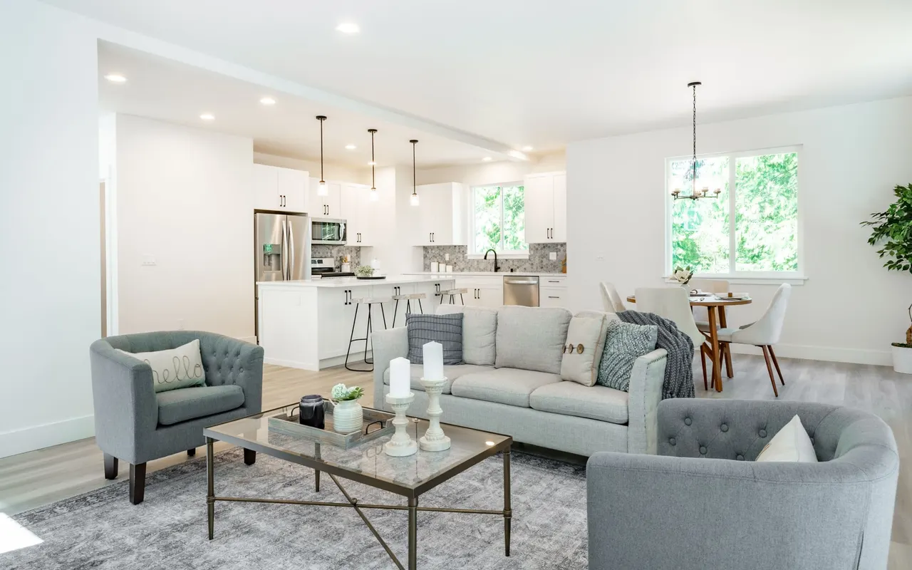 Open plan living room in soft greys looking through to a white kitchen and a window seat